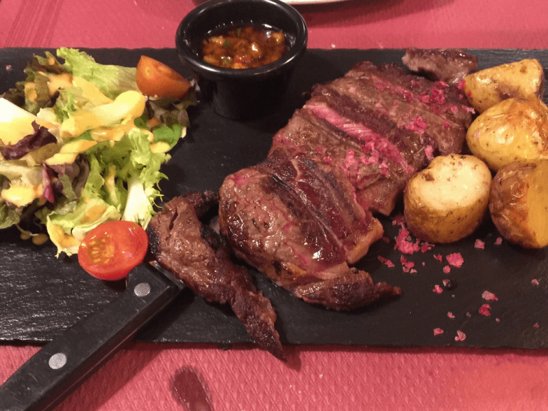 Filete a la parrilla en lonchas con patatas asadas y ensalada sobre pizarra